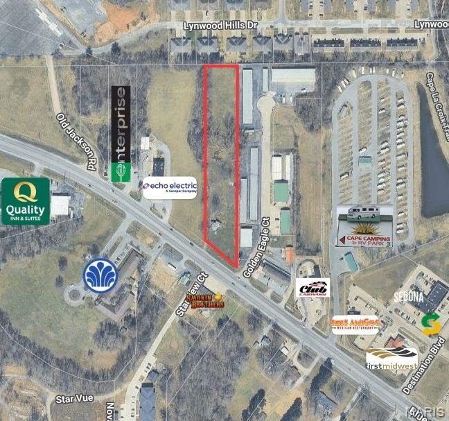 Aerial view with the parcel boundary outlined among surrounding businesses